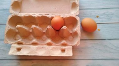 Bir kadının eli yumurta kutusundan bej bir yumurta alır.