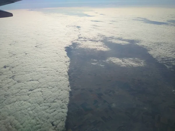 Kilátás a repülőgép ablakából a parton és a felhők — Stock Fotó