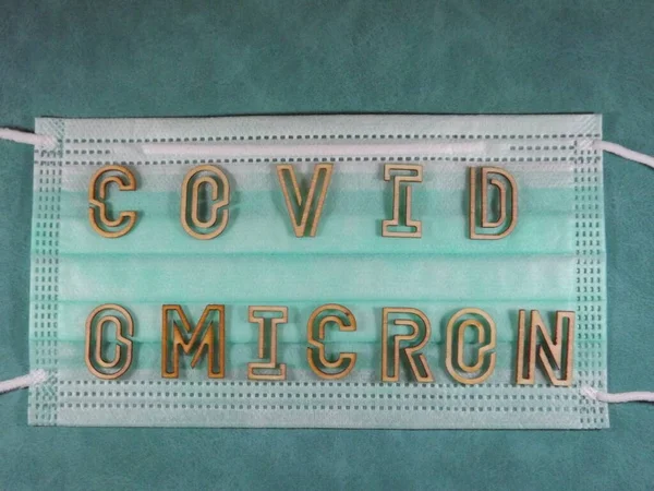 Η λέξη covid παραλλαγή omicron με ξύλινα γράμματα στη μάσκα προσώπου — Φωτογραφία Αρχείου