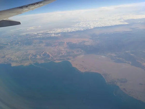 Zicht vanuit het raam van het vliegtuig op de kustlijn en wolken — Stockfoto
