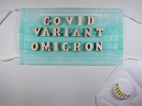 Het woord covid variant omicron in houten letters op het gezichtsmasker — Stockfoto