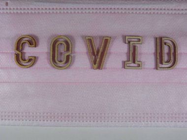 Yüz maskesi üzerinde ahşap harflerle 