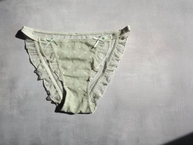 Açık yeşil kadın külotu ve gri bir arka planda fırfırları var.