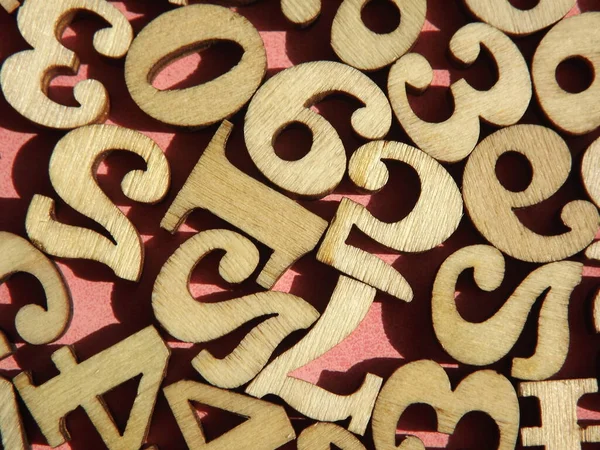 Wooden numbers are randomly arranged on pink suede — Stock Photo, Image