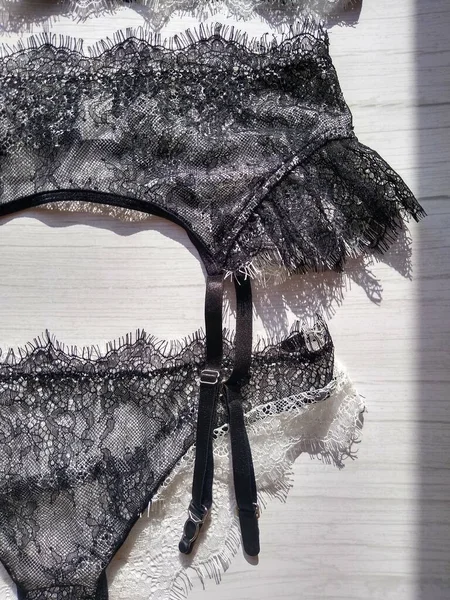 Een set zwart-wit guipure ondergoed, bestaande uit een beha, een string en een kousenband — Stockfoto