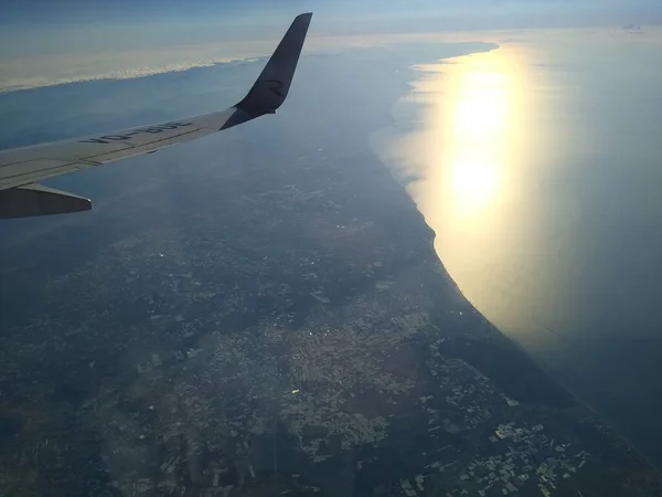 Kıyı şeridi ve bulutlardaki uçağın penceresinden bak. — Stok fotoğraf