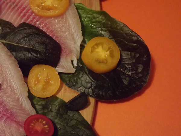 El proceso de cocción del filete de tilapia con tomates, aceitunas y hojas de lechuga — Foto de Stock