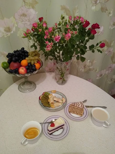 Frühstück für zwei Personen mit Tee und Kuchen mit Rosen in einer Vase — Stockfoto