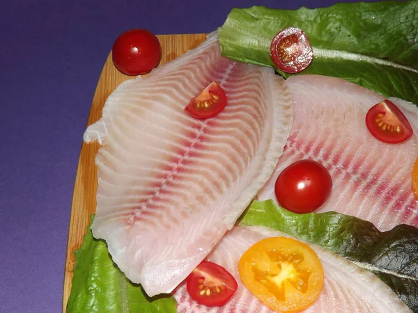 Processen för tillagning av tilapia fiskfilé med tomater, oliver och salladsblad — Stockfoto