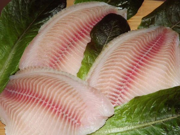 Fresh fish fillet with lettuce leaves, the cooking process — Stockfoto