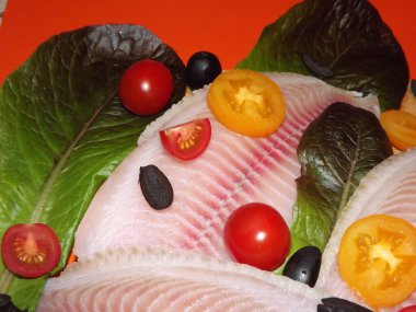 Domatesli, zeytinli ve marullu tilapia balığı filetosu pişirme işlemi