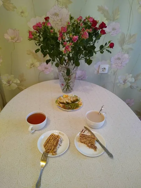 Café da manhã para dois com chá e bolos com rosas em um vaso — Fotografia de Stock