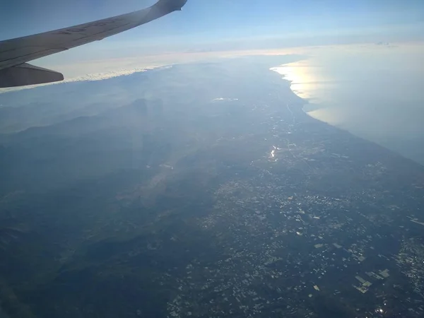 Vista desde la ventana del avión en la costa y las nubes — Foto de Stock