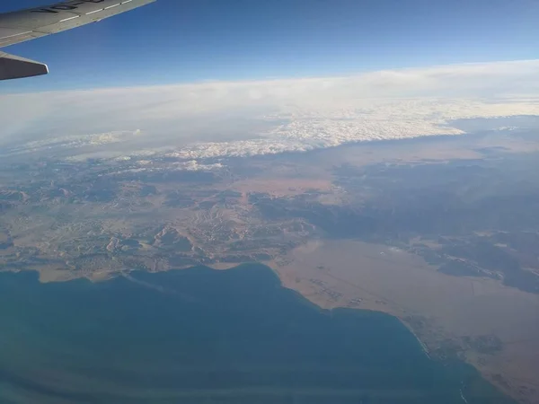 Widok z okna samolotu na wybrzeże i chmury — Zdjęcie stockowe