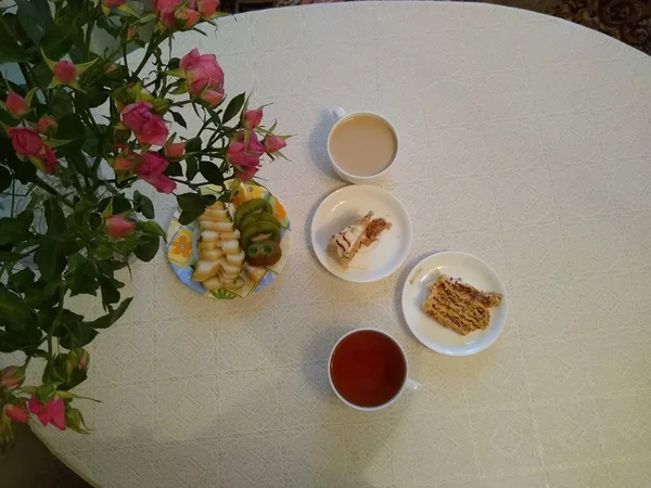 Frühstück für zwei Personen mit Tee und Kuchen mit Rosen in einer Vase — Stockfoto