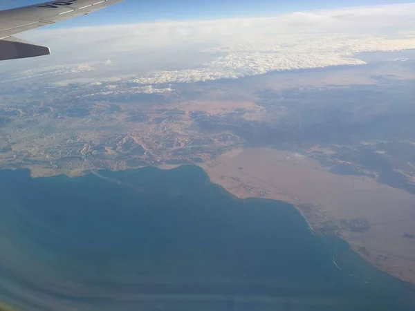 Vista desde la ventana del avión en la costa y las nubes — Foto de Stock