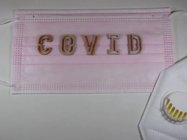 Het woord covid variant omicron in houten letters op het gezichtsmasker — Stockfoto
