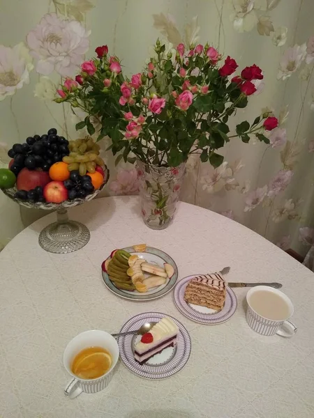 Frühstück für zwei Personen mit Tee und Kuchen mit Rosen in einer Vase — Stockfoto
