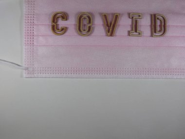 Yüz maskesi üzerinde ahşap harflerle 