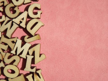 Arkaplan olarak pembe süet üzerine İngiliz alfabesinin ahşap harfleri