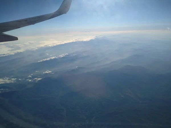 Blick aus dem Flugzeugfenster auf die Küste und Wolken — Stockfoto