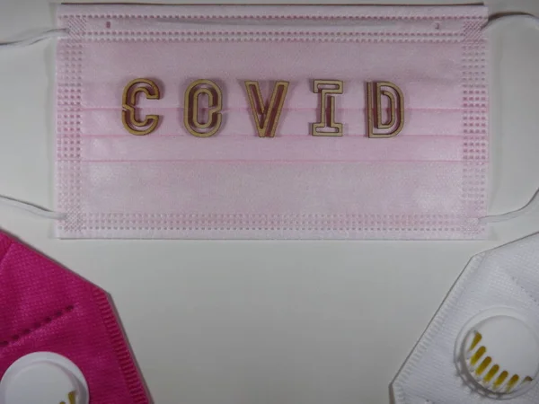 Het woord covid variant omicron in houten letters op het gezichtsmasker — Stockfoto