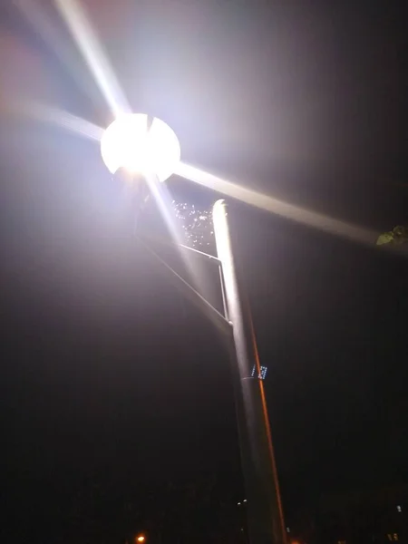 Telaraña en la parte superior de un poste de luz entre tres linternas en la noche — Foto de Stock