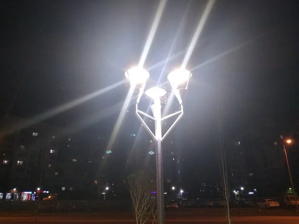 Telaraña en la parte superior de un poste de luz entre tres linternas en la noche — Foto de Stock