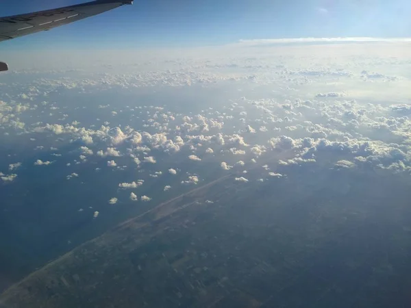 Vista desde la ventana del avión en la costa y las nubes — Foto de Stock