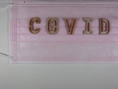 Yüz maskesi üzerinde ahşap harflerle 