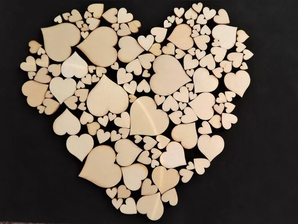 Wooden hearts on a black background as a postcard for the holidays — Stock Photo, Image