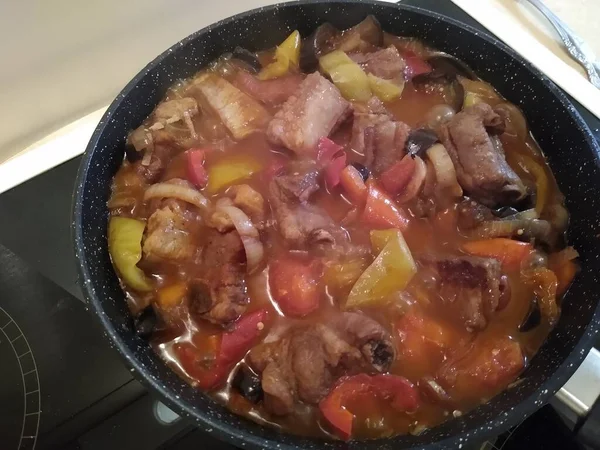 Le processus de cuisson de la viande sur les os avec des légumes : oignons, carottes, poivrons, aubergines. — Photo