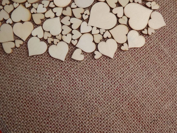 Corazones de madera de diferentes tamaños en tela de yute como tarjeta de felicitación del día de San Valentín — Foto de Stock