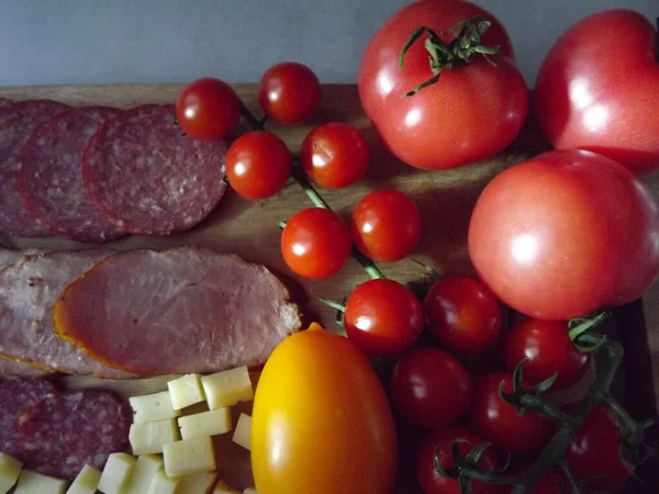 훈제 소시지 4 가지를 치즈, 빨강 과 노랑 토마토, 그리고 체리 토마토와 함께 썰어서 먹는다 — 스톡 사진