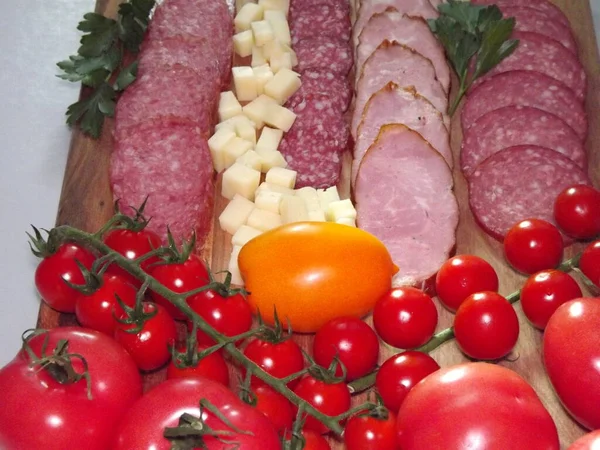 Fatias de salsicha defumada de quatro variedades com queijo e tomates vermelhos e amarelos e tomates cereja — Fotografia de Stock