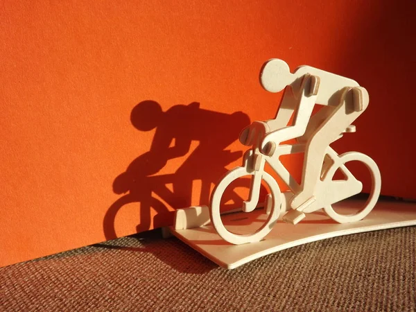 Ciclista em uma bicicleta feita de madeira em um fundo laranja — Fotografia de Stock