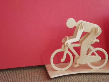 Pembe arka planda tahtadan yapılmış bisiklete binen bisikletçi.
