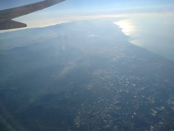 Vue de la fenêtre de l'avion sur le littoral et les nuages — Photo