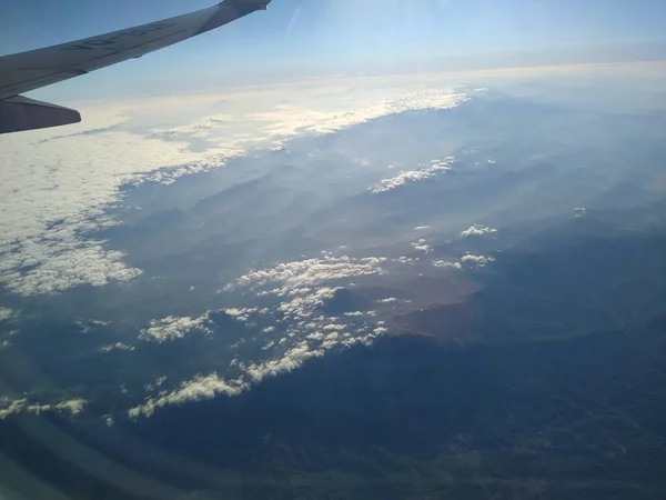 Blick aus dem Flugzeugfenster auf die Küste und Wolken — Stockfoto