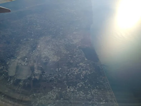 Vista desde la ventana del avión en la costa y las nubes — Foto de Stock