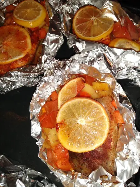 El proceso de cocción del pescado de trucha roja con limón y verduras en papel de aluminio — Foto de Stock