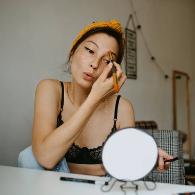 Evde makyaj yapan çekici bir kadın. 