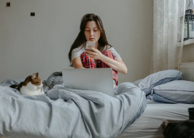 Cep telefonu olan kadın hasta yatağında yatıyor.