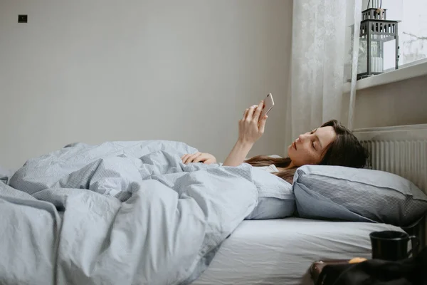 ベッドの上の自宅で病気になった携帯電話の女性は — ストック写真