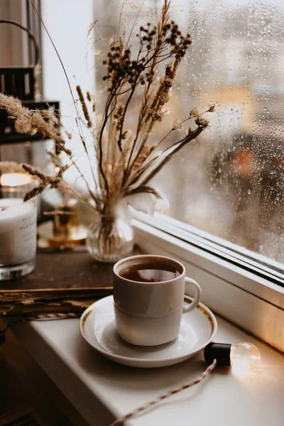 窓にはコーヒーカップとドライブラウンの花が — ストック写真