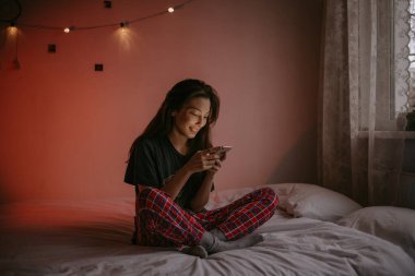 Evde cep telefonu olan genç bir kadın.