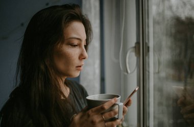 Evde cep telefonu olan genç bir kadın.