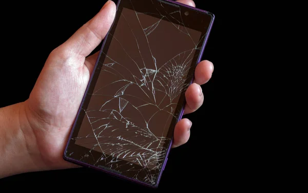 Smartphone with highly broken screen in women hand on black background