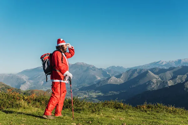 Genç Noel Baba sırt çantasıyla dağların uzak yerlerine hediye götürmek için yürüyüşe çıktı. Noel ve tatil konsepti.