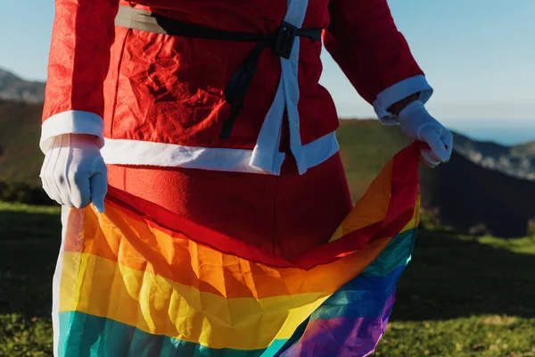 サンタ クラスの服を着て虹色のLgbtプライドの旗を掲げてる クリスマスのコンセプトは — ストック写真